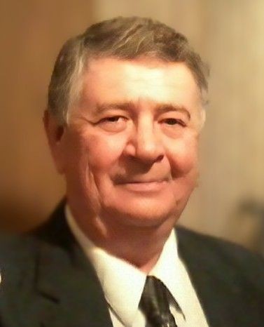 Elderly man in a suit and tie smiling at the camera.