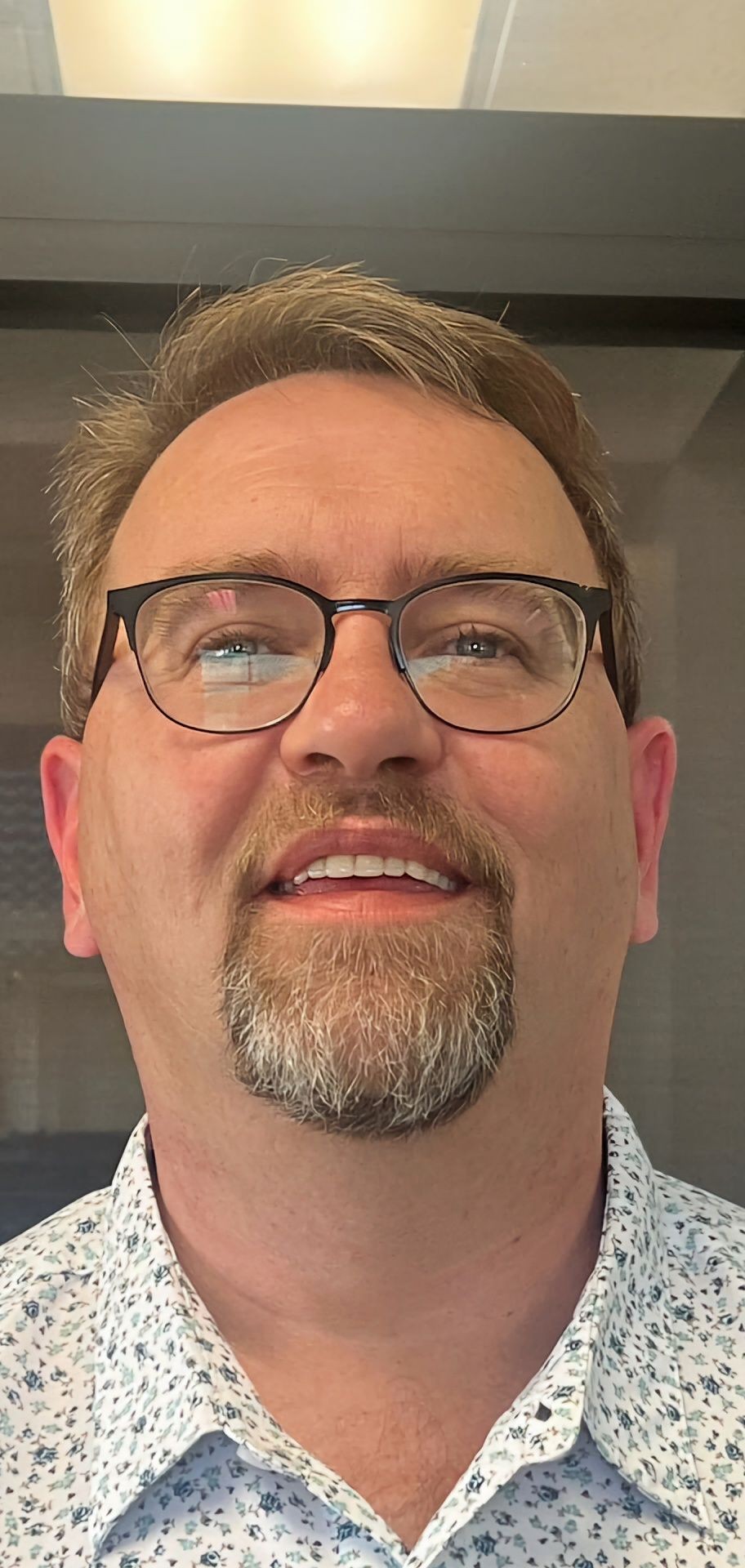 Person wearing glasses and a floral patterned shirt, looking upwards.